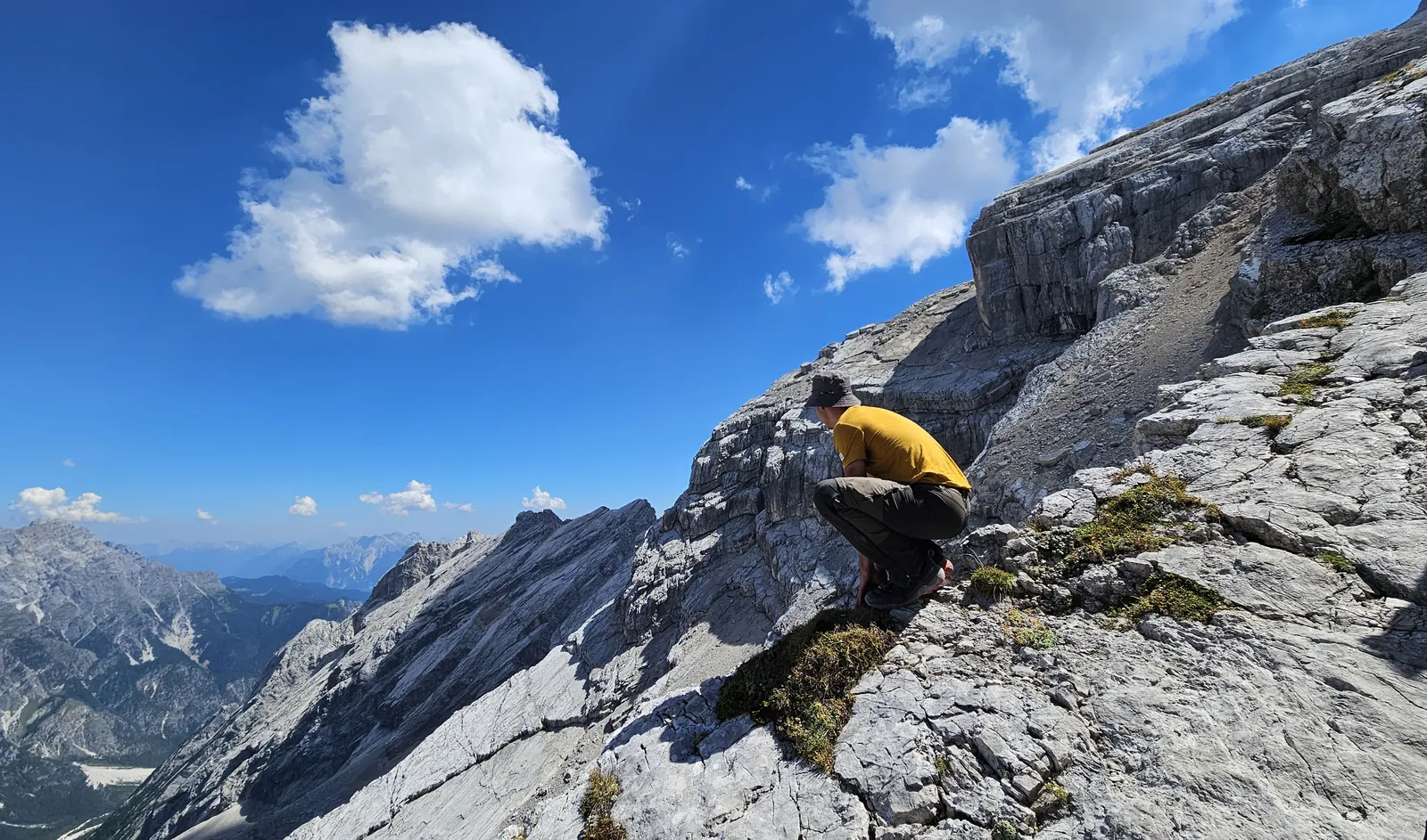 A climber in a yellow top on a steep rocky mountainside